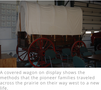 A covered wagon on display shows the methods that the pioneer families traveled across the prairie on their way west to a new life.